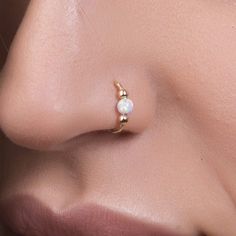 a woman's nose with a pearl and gold nose ring on top of her nose