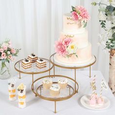 three tiered cake stands with cupcakes and flowers in vases on the table