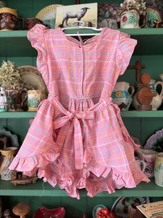 Sweet well constructed vintage romper. Smaller scale plaid with pink background with blue, yellow and white accents. Ruffles galore. Loose fitting short with button closure in the style of a diaper with an apron tie skirt. Open back with tie at the neck. Needs a little repair along the neck line. Good vintage condition with small stain noted in the crotch area. Tag removed, maker and size unknown.  Measures 12 inches across the top and waist,  arm opening 6 inches measured flat.  The rest is free flowing. Pink Retro Jumpsuits And Rompers For Spring, Retro Pink Jumpsuits And Rompers For Summer, Retro Pink Summer Jumpsuits And Rompers, Pink Retro Summer Jumpsuits And Rompers, Plaid Romper, Vintage Romper, Cary Nc, Tie Skirt, Free Flowing