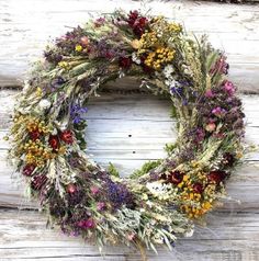 a wreath made out of dried flowers sitting on top of a wooden wall