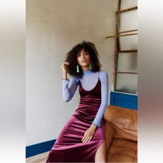 a woman in a purple dress sitting on a couch