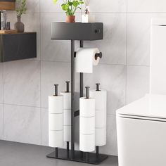 three rolls of toilet paper sitting on a stand next to a toilet