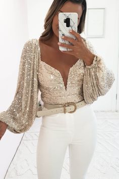 Get Christmas Party ready with our stunning Astria Sequin Top. This top is finished in super sparkly sequins and its long puffy sleeves give it a glamorous look. Exclusive to Oh Hello Clothing Exclusive Colour: Beige sequin Fabric: Stretchy 90% polyester 10% spandex Sizing: True to size Model wears: Size small = UK 8 Model height: 5ft 3 Sleeve length: 64cm Care: Gentle hand wash Sequin Bodysuit Outfit, Sequin Blouse Outfit, Sequin Top Outfit Party, Gold Tops Outfit, Sparkly Top Outfit, Sparkly Sequin Top, Sequins Top Outfit, Oh Hello Clothing, White Skirt Outfits