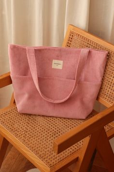 a pink tote bag sitting on top of a wooden chair next to a window