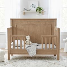 a baby crib with a teddy bear sitting on the bed in front of it