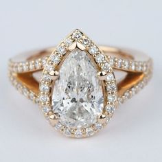 a pear shaped diamond ring with two rows of diamonds around the band and an oval center