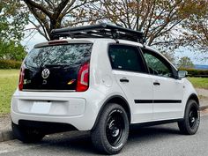 a small white car parked on the side of the road with its roof rack open