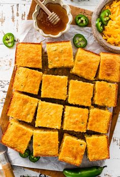 some food that is on a cutting board and next to it are green peppers, jalapenos, and cheese