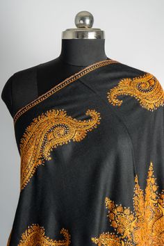 Radiating with intricate Sozni embroidery, this black merino wool shawl is adorned with a magnificent sunburst design surrounded by golden paisleys. The hand-embroidered details in vibrant yellow-gold bring the fabric to life, making this shawl a true masterpiece of Kashmiri craftsmanship. A statement of luxury and elegance, this shawl is perfect for making a grand entrance at any event. The warmth of merino wool combined with the timeless artistry of Sozni embroidery ensures you stand out with Luxury Raw Silk Pashmina Shawl With Zari Work, Elegant Luxury Shawl With Intricate Embroidery, Luxury Gold Elegant Shawl, Luxury Festive Shawl With Woven Motifs, Luxury Ceremonial Pashmina Shawl With Zari Work, Luxury Chikankari Embroidered Shawl, Luxury Black Shawl With Motifs, Luxury Handmade Shawl For Gift, Luxury Embroidered Elegant Pashmina Shawl