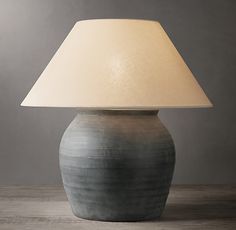 a lamp that is on top of a wooden table with a white shade over it