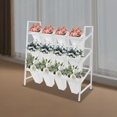 three white planters with flowers in them on a shelf