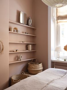 a bed sitting under a window next to a shelf filled with vases and other items