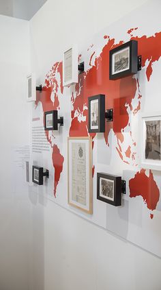 a world map is mounted on the wall with framed photos and pictures hanging from it's sides