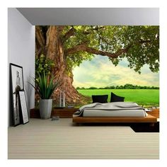 a bedroom with a large tree mural on the wall and bed in the foreground