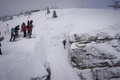 several people are standing on the side of a snowy mountain