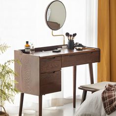 a wooden desk with a mirror and other items sitting on it in front of a window