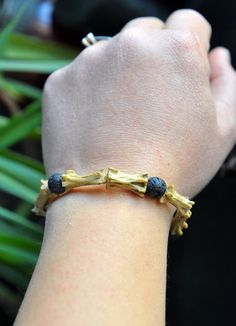 a person's arm with a bracelet made out of gold and black beads on it