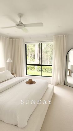 a large white bed sitting in a bedroom next to a window