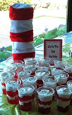 a table topped with lots of cups filled with red and white jello next to a sign that says get the hot fudges