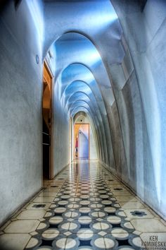 a long hallway with white walls and black and white tile flooring that has circles on it