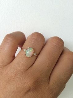 a woman's hand with a ring on it that has an opal in the middle