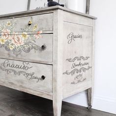 an old dresser painted with floral designs and writing on the drawers is sitting in a room