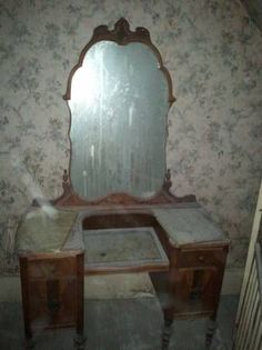 an antique vanity with mirror and stool in the corner