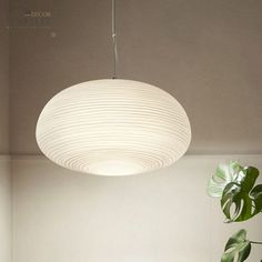 a white lamp hanging from the ceiling next to a potted plant