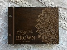 a wooden wedding guest book with lace on the edge and an intricate laser engraved design