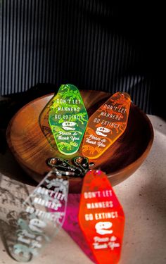 three glass bottle openers sitting on top of a wooden bowl next to each other