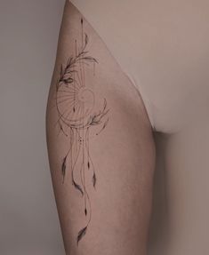 a woman's thigh with an arrow and dream catcher tattoo on her left side