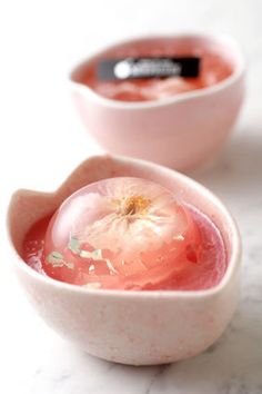 there are two small bowls with food inside of them on the counter top, one is filled with liquid and the other has an apple in it's bowl