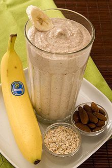 a banana sitting on top of a white plate next to a glass filled with oatmeal