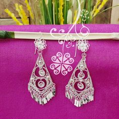 Beautiful and stunning handmade Mexican Filigree Earrings. Each piece is meticulously created out of copper wire and spun into a beautiful design. To give it the final touch artisans dipped into silver plate for it's elegant silver color. This accessory is an important part of the traditional Tehuana outfit from Oaxaca, Mexico. Look elegant while wearing Mexico's culture with this one of a kind earrings! Approximate length: 3.5-4 in Need more than one? Ask us about our combined flat rate shipmen White Bohemian Earrings With Intricate Design, White Intricate Design Dangle Earrings, Bohemian Silver Bridal Earrings With Latkans, Bohemian Bridal Earrings With Latkans In Silver, Bohemian Bridal Silver Earrings With Latkans, Traditional Metal Dangle Clip-on Earrings, Traditional Dangle Flower Earrings For Festivals, Traditional Dangle Flower Earrings For Pierced Ears, Traditional Silver Plug Earrings For Party