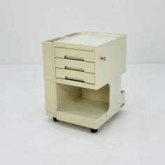 a white cabinet with two drawers on wheels and one drawer open to show the contents