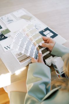 a woman is holding some paint samples on a table