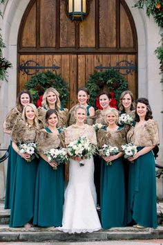 a group of women standing next to each other in front of a door with wreaths