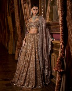 This lehenga set features intricate embroidery in sequin, bead and crystal on a deep mustard tissue organza base. The elbow sleeve blouse has tassels at sleeve hem and waist and is paired with a contrasting maroon tissue dupatta with matching heavy embroidery.From Seema Gujral's Falaknuma collection. DELIVERY TIMEPlease allow 8-12 weeks for your outfit to arrive. FABRIC DETAILSTissue Organza Professional cleaning only. Glamorous Organza Choli With Dupatta, Glamorous Embellished Lehenga For Eid, Brown Anarkali Set With Dupatta For Festive Occasions, Festive Brown Anarkali Set With Dupatta, Glamorous Traditional Wear With Dupatta For Reception, Glamorous Reception Traditional Wear With Dupatta, Sequined Raw Silk Lehenga For Reception, Glamorous Tissue Silk Lehenga For Designer Wear, Glamorous Tissue Silk Sets With Zari Work