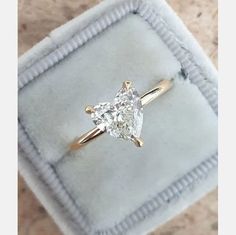 an engagement ring with a pear shaped diamond in it on a velvet box that is sitting on top of a carpeted surface