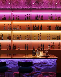 an illuminated bar with several bottles on the shelves