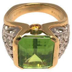 By designer Richard Krementz, known for high quality and exceptional stones. This ring is an attention grabber! It's beautiful green colored Peridot is complemented by a platinum, 18K yellow gold and diamond design/mounting. Emerald cut peridot in partial bezel setting- approximately 11.7mm X 11.0mm 26 round diamonds in various sizes - approximately .74tdw 2 round orange (sapphires) on each side Stamped "750", "PLAT", "RKG" and "1866" Approximate size is 5.5 (can be sized) 7.3dwt Attention Grabber, Yellow Ring, Yellow Rings, Jewelry Fashion Trends, Orange Sapphire, Diamond Design, Bezel Setting, Emerald Cut, Diamond Rings