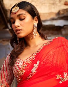 Presenting a striking red kalidar chiffon bridal sari adorned with exquisite thread and pearl embroidery, elegantly paired with an embroidered raw silk blouse. This ensemble radiates sophistication and timeless beauty, making it an ideal choice for a bridal occasion.