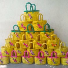 yellow baskets with pink handles are stacked on top of each other in front of a white wall