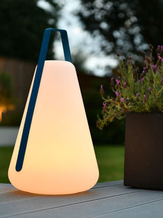 a white and blue lamp sitting on top of a table next to a potted plant