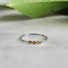 The delicate lace-like openings in this ring are created by twisting and hammering two strands of metal. In this ring, the central twist is in 14k gold, set against a sterling silver band. With its light elegance and hand-forged charm, this dainty ring is perfect for stacking with others or wearing by itself. - 14k recycled gold and sterling silver with a high shine finish - Central motif is approximately 10mm x 2.5mm; 1.25mm band - Crafted with joy in San Francisco Sample ring shown in a size 7 Stackable Twisted Rings For Promise, Modern Twist Stackable Rings For Promise, Modern Twist Stackable Twisted Promise Rings, Modern Twisted Promise Ring, Modern Twist Twisted Promise Ring, Modern Twisted Shape Promise Ring, Modern Twist Stackable Promise Rings, Mixed Metal Ring, Two Tone Ring