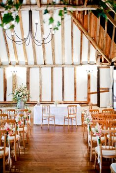 the inside of a barn with tables and chairs set up for a formal function or wedding