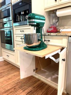 a green mixer sitting on top of a wooden counter in a kitchen next to an oven