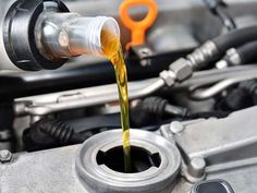 oil being poured into a car's engine with an orange wrench in the background