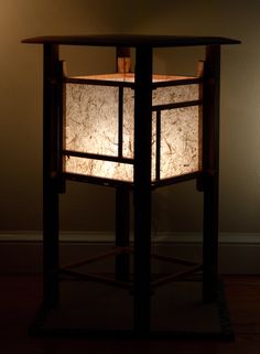 a table with a lamp on top of it in front of a wall and floor