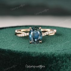 a blue and white diamond ring sitting on top of a green velvet box